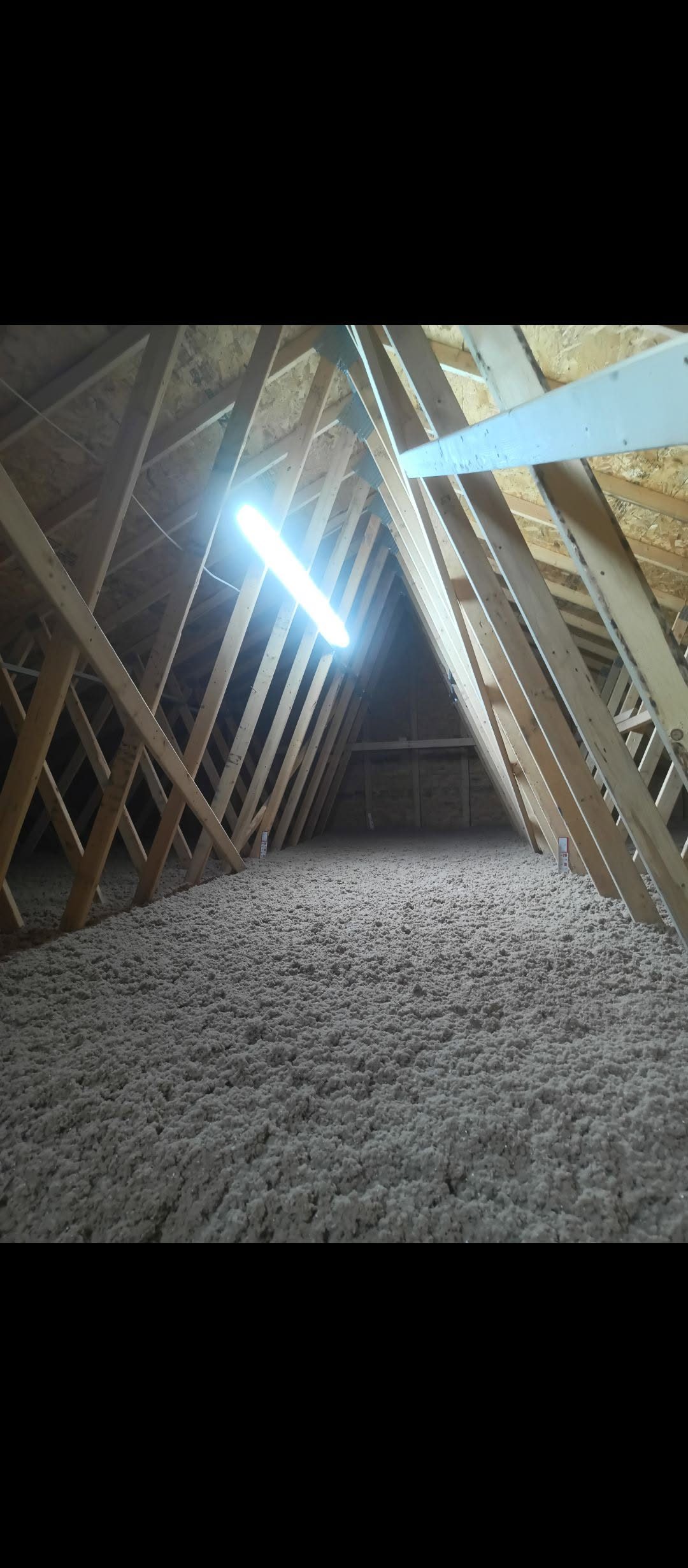 Finished attic with a deep even blanket of blown-in insulation between the trusses